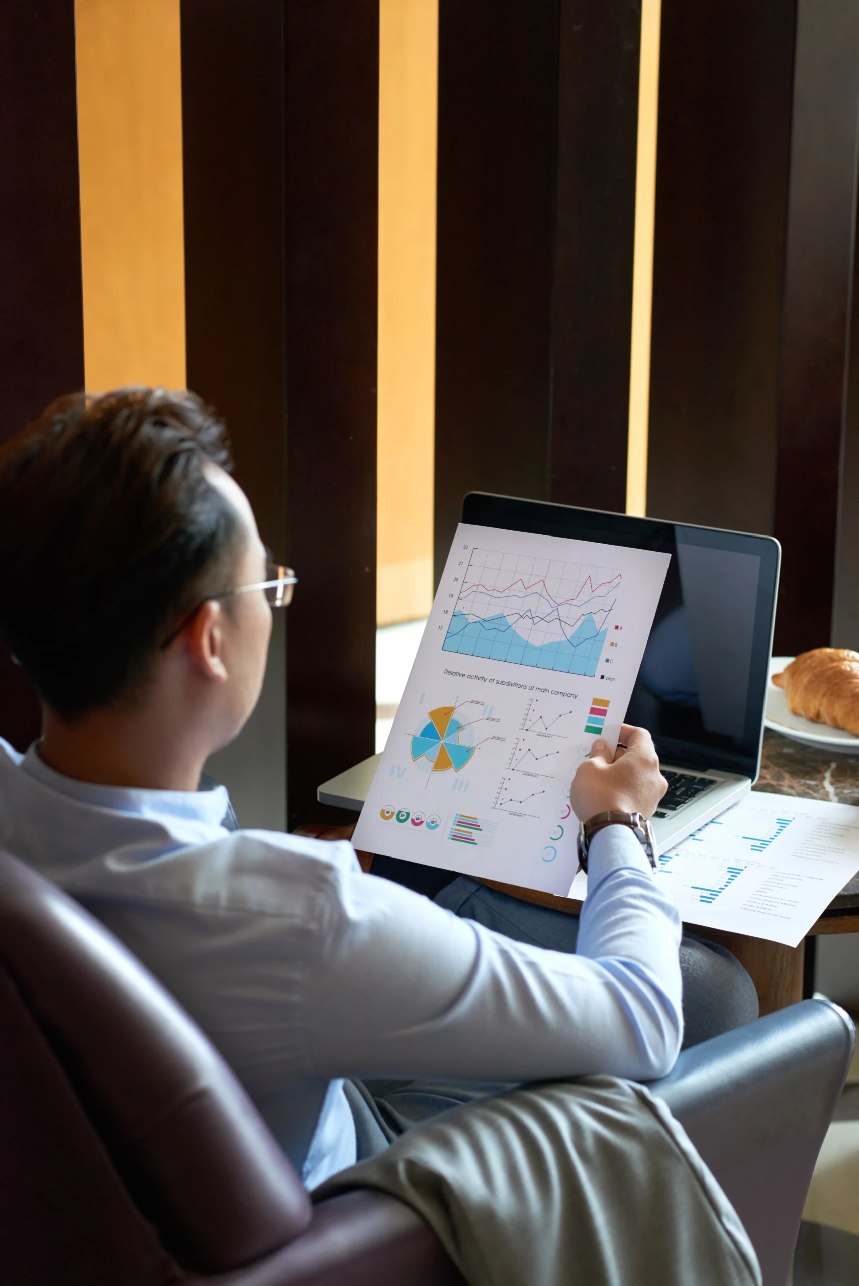 rear view man seated armchair cafe analyzing diagrams charts before presentation